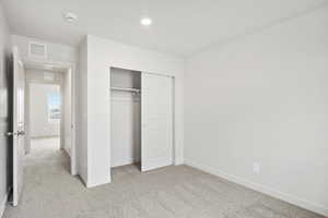 Unfurnished bedroom with light colored carpet, a closet, and recessed lighting