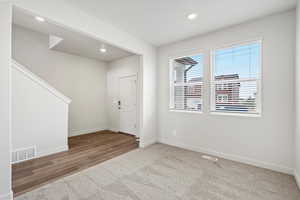 Foyer with light carpet, recessed lighting, and stairway