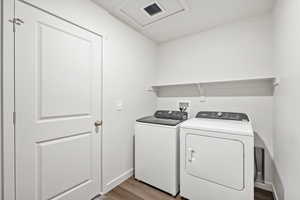 Laundry area with wood finished floors and washer and clothes dryer