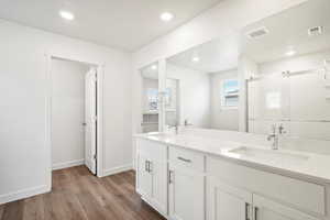 Full bathroom with a stall shower, dark wood finished floors, double vanity, and recessed lighting