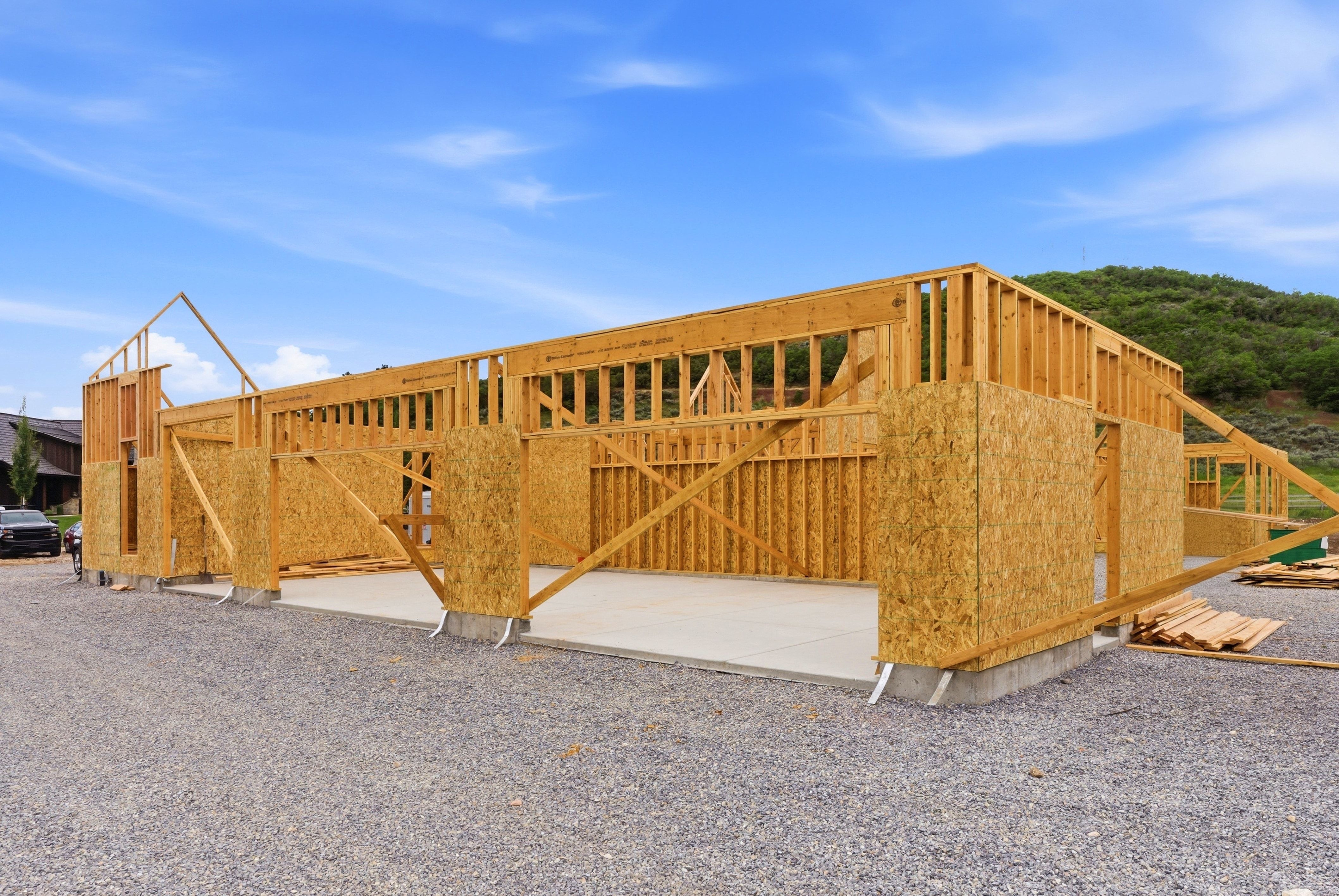 New construction framing with visible foundation, oriented strand board sheathing, and a concrete slab