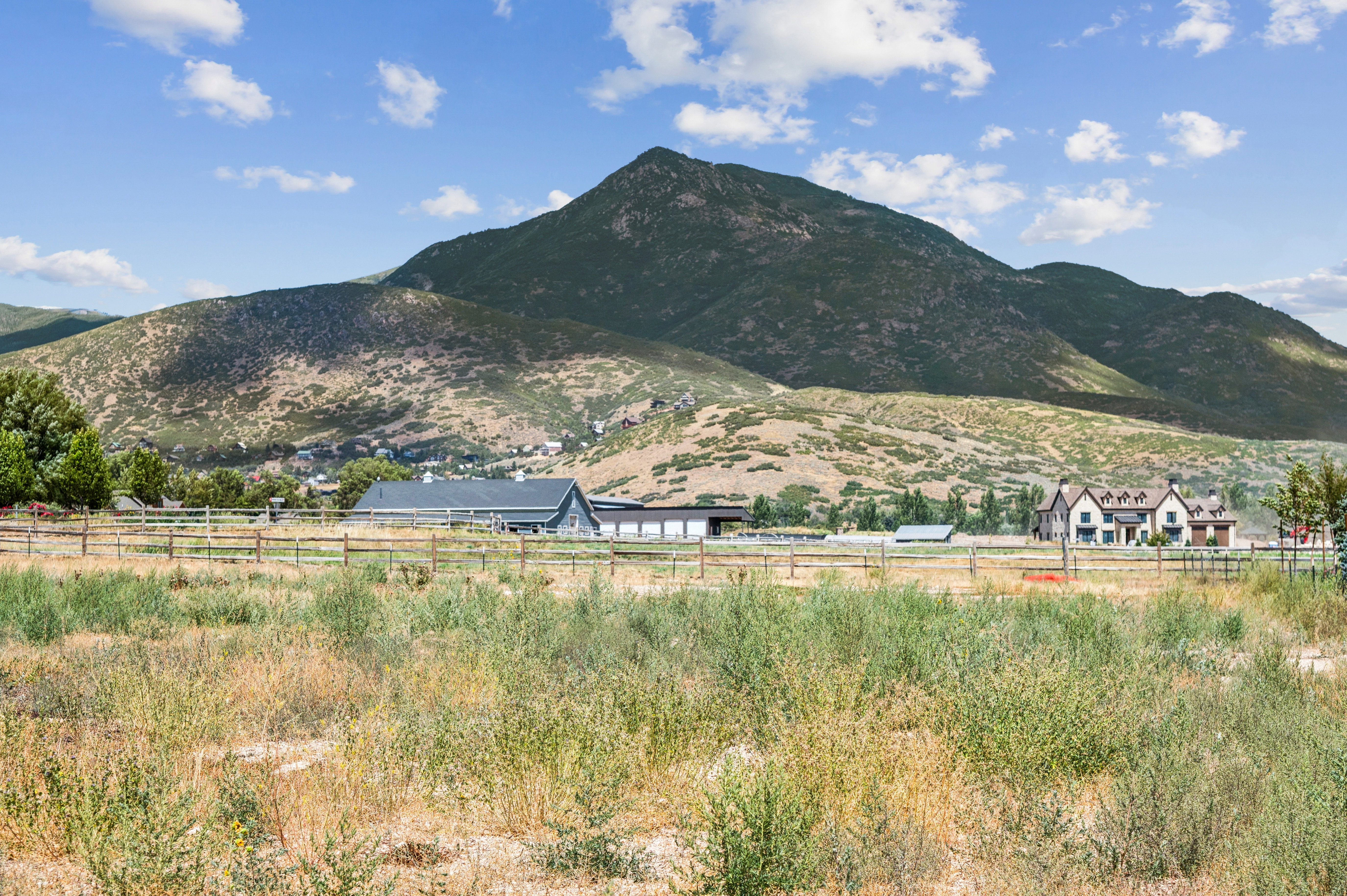 Expansive undeveloped land featuring a perimeter fence and distant mountain backdrop
