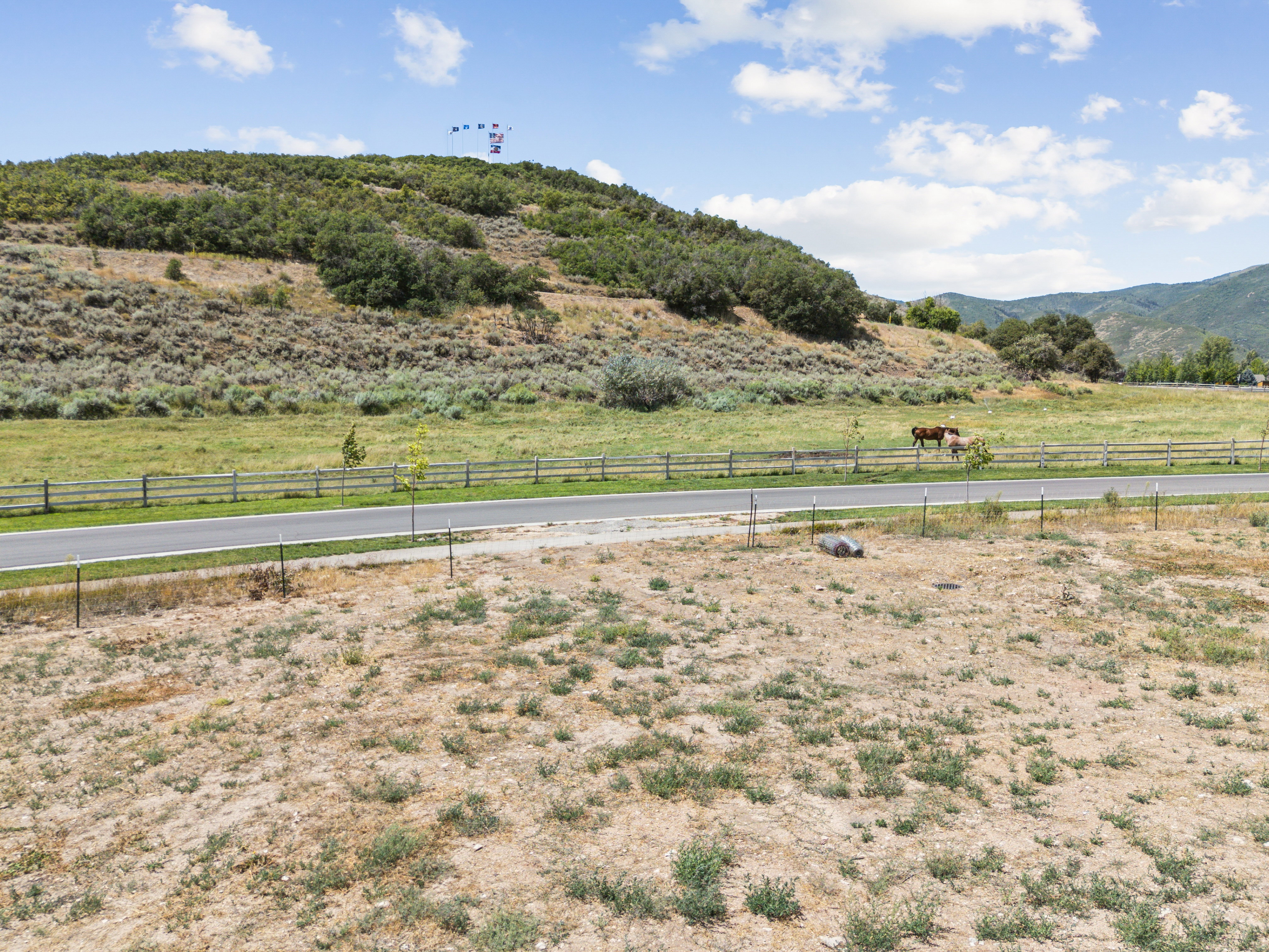 Expansive undeveloped land featuring a paved road, natural hillside, and distant mountain range