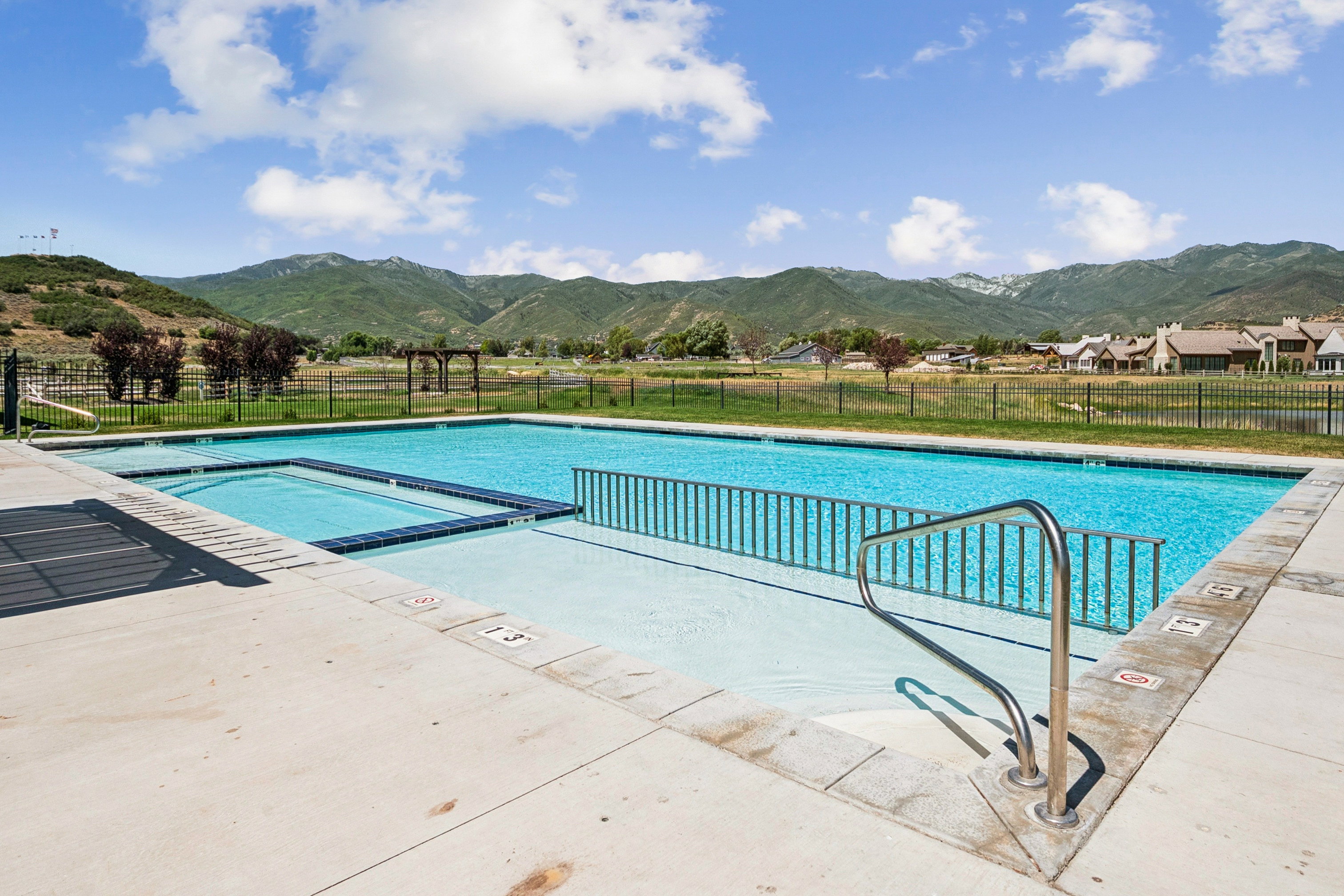 Swimming pool featuring an integrated spa, concrete deck, and mountain backdrop