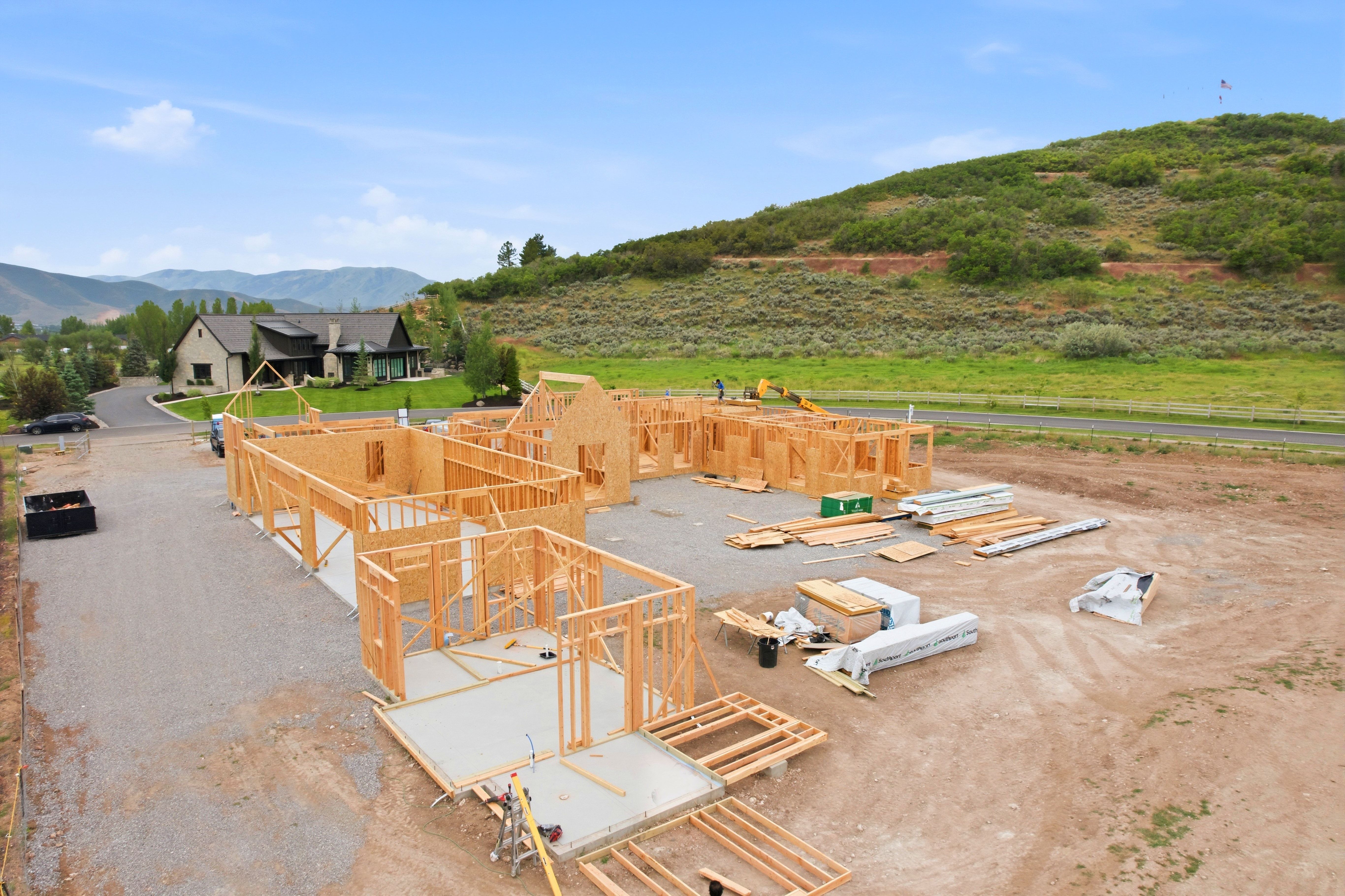 New construction framework with an expansive footprint, featuring wood framing, concrete slab foundations, and a gravel lot