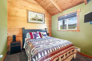 Bedroom with wooden walls, wooden ceiling, lofted ceiling, and baseboard heating