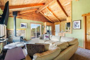 Carpeted living room featuring a wood stove, wood ceiling, a chandelier, a textured wall, and wooden walls