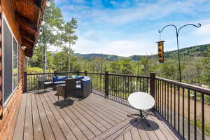 Deck with an outdoor living space, a wooded view, and a mountain view