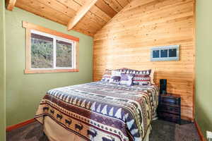 Carpeted bedroom featuring wood walls and wooden ceiling