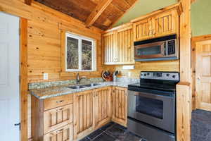 Kitchen featuring appliances with stainless steel finishes, wooden ceiling, light stone countertops, and wood walls