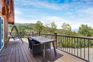 Wooden deck with outdoor dining area and a view of trees
