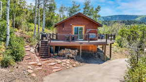 Back of property featuring a forest view, stairway, and a deck