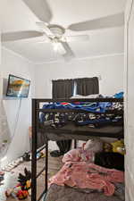 Bedroom with wood finished floors, ornamental molding, a ceiling fan, and a textured ceiling
