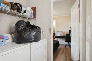 Laundry room featuring washing machine and dryer, wood finished floors, ornamental molding, and an office area