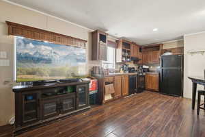Kitchen featuring crown molding, black appliances, dark wood finished floors, open shelves, and glass insert cabinets