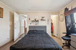 Bedroom featuring ornamental molding and wood finished floors