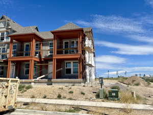 View of front of property with a shingled roof and a balcony