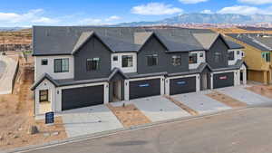 Modern farmhouse with a mountain view, driveway, stucco siding, and an attached garage