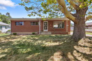 Single story home with a front lawn and brick siding