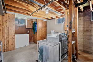 Washroom featuring washer and clothes dryer and wooden walls
