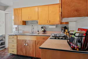 Kitchen with light countertops, brick patterned floors, and black stovetop