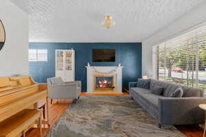 Living room featuring wood finished floors, a fireplace, and a textured ceiling