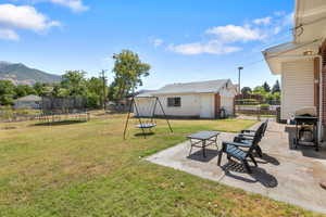 View of yard with a trampoline, a patio area, and an outdoor structure
