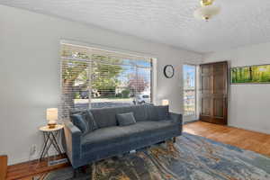 Living area with plenty of natural light, a textured ceiling, and wood finished floors