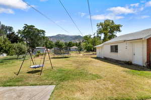 View of grassy yard with a trampoline, a mountain view, and a playground