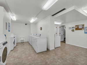 Shared laundry room featuring washer and dryer and light tile patterned flooring