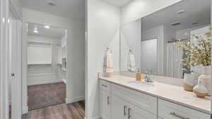 Bathroom with vanity, wood finished floors, a walk in closet, and curtained shower