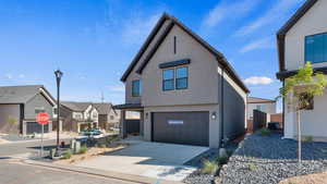 View of front of home featuring a garage, stucco siding, driveway, and a residential view