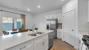 Kitchen featuring light wood-style flooring, appliances with stainless steel finishes, white cabinetry, light countertops, and recessed lighting