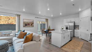 Kitchen featuring open floor plan, wood finished floors, white cabinetry, and recessed lighting