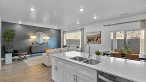 Kitchen with light wood-style floors, light countertops, recessed lighting, open floor plan, and white cabinets