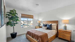 Carpeted bedroom featuring baseboards and a textured ceiling