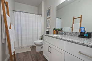 Bathroom with wood finished floors, vanity, a shower with curtain, and a textured ceiling