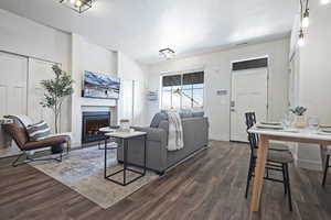 Living area with a lit fireplace, a textured ceiling, and dark wood finished floors