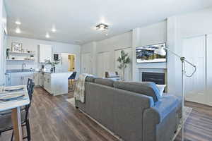 Living area with a glass covered fireplace, dark wood-style flooring, and recessed lighting