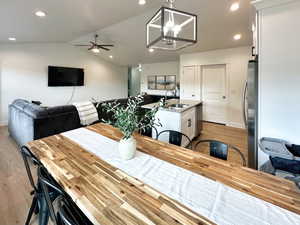 Dining area featuring lofted ceiling, light wood-type flooring, a chandelier, recessed lighting, and a ceiling fan