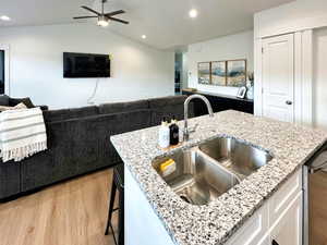 Kitchen featuring open floor plan, light stone countertops, light wood-style flooring, white cabinetry, and recessed lighting
