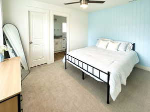 Bedroom with light carpet, ceiling fan, and connected bathroom