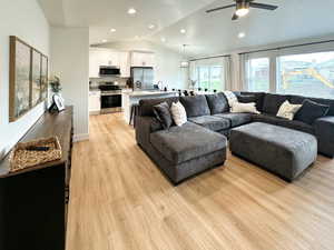 Living area with light wood-style flooring, vaulted ceiling, ceiling fan, recessed lighting, and a textured ceiling