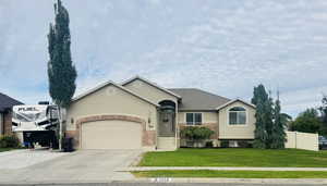 Ranch-style house with stucco siding, driveway, an attached garage, and brick siding