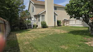 Rear view of house featuring a fenced backyard, a deck, and roof with shingles