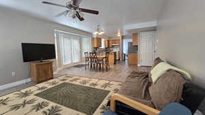 Living room with light wood-style floors, ceiling fan, and a chandelier