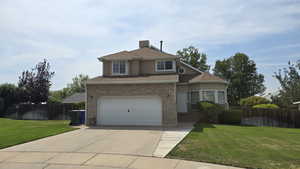 Traditional-style home with driveway, a garage, brick siding, a shingled roof, and stucco siding