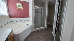 Full bathroom featuring a stall shower, a jetted tub, tile patterned flooring, and vanity