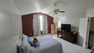 Bedroom featuring light colored carpet, vaulted ceiling, a ceiling fan, and a textured ceiling