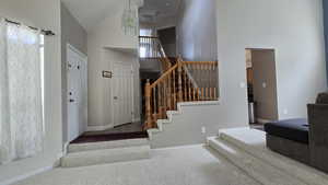 Stairway featuring high vaulted ceiling, carpet flooring, and a chandelier